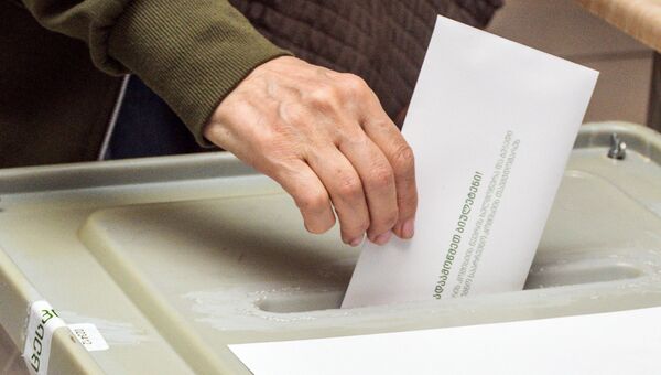 Избиратель опускает бюллетень в урну на выборах президента Грузии на одном из избирательных участков в Тбилиси. 28 октября 2018