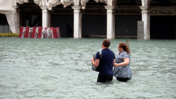 Люди на затопленной площади Святого Марка во время сезонного половодья в Венеции, Италия. 29 октября 2018 года