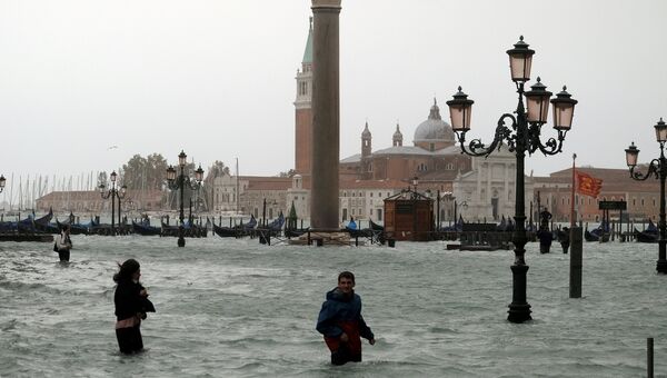Люди на затопленной площади Святого Марка во время сезонного половодья в Венеции, Италия. 29 октября 2018 года