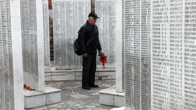 Мужчина возлагает цветы к мемориалу памяти жертв политических репрессий