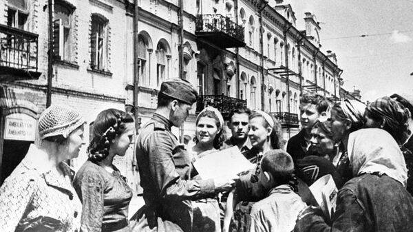 Советский солдат показывает жителям освобожденного Минска газету Правда