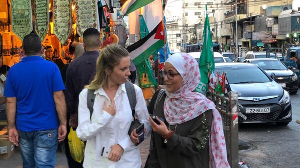 Женщины идут рядом с торговыми рядами по улице Аммана, Иордания 