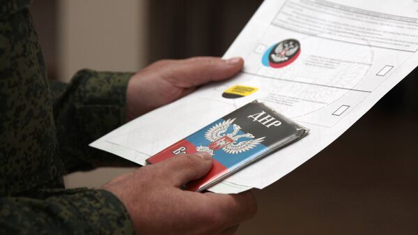 Военнослужащий Донецкой Народной Республики держит воинский билет и избирательные листы для голосования на выборах в ДНР
