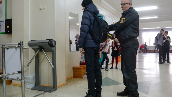 Сотрудник службы безопасности проверяет ученика в средней общеобразовательной школе