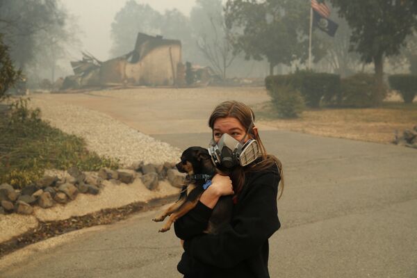 Девушка с собакой возле сгоревшего дома в Калифорнии, США