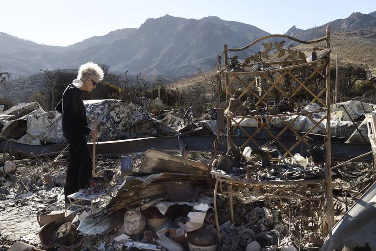 Женщина стоит на месте сгоревшего дома в Калифорнии, США