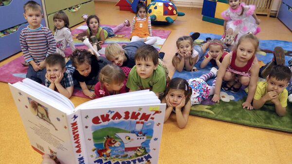 Воспитатель читает детям сказку в комнате отдыха детского сада. Архивное фото