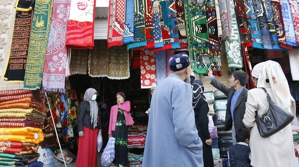 Уйгурские мусульмане выбирают молельные коврики на рынке в Хотане. Архивное фото