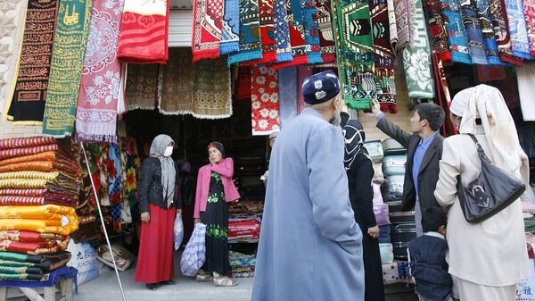 Уйгурские мусульмане выбирают молельные коврики на рынке в Хотане 