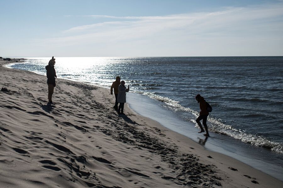 Отдыхающие гуляют по берегу Балтийского моря в поселке Янтарный