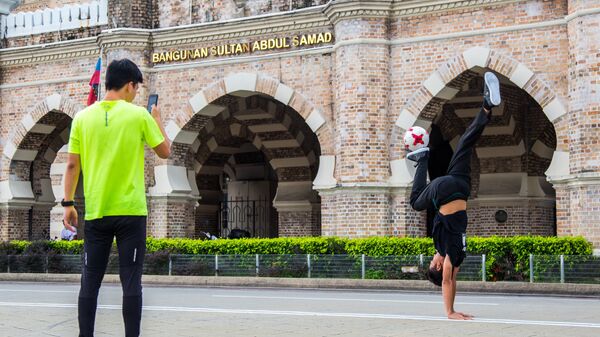 Молодые люди играют в мяч перед заданием султана Абдул-Самада на площади Мердека в Куала-Лумпуре