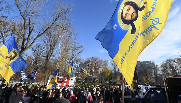 Активисты крайне правых групп держат плакаты и христианские флаги, протестуя против марша прав трансгендеров в Киеве. 18 ноября 2018