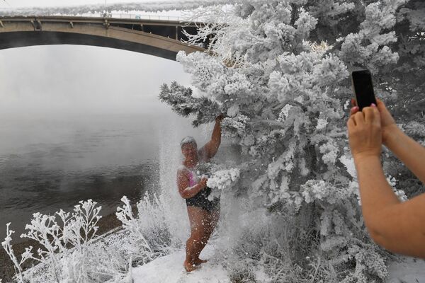 Участницы клуба зимнего плавания Криофил фотографируются у заснеженных деревьев на берегу реки Енисей в Красноярске