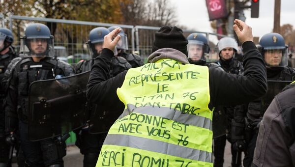 Участник акции протеста против роста цен на бензин желтые жилеты и полицейские в Париже. 24 ноября 2018