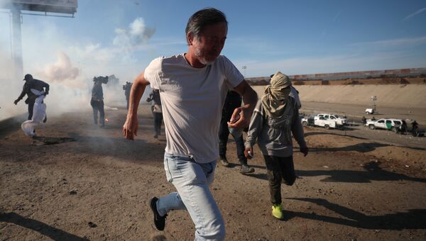 Мигранты бегут от слезоточивого газа, распыленного американскими пограничниками. 26.11.2018