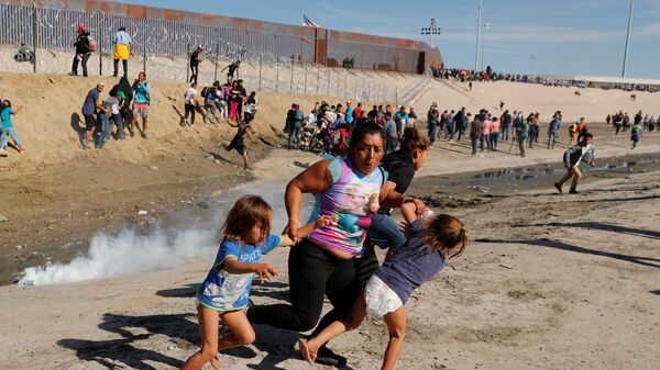 Мигранты из Гондураса бегут от слезоточивого газа, распыленного американскими пограничниками. 26 ноября 2018