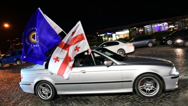 Автомобиль с флагом правящей партии Грузинская мечта и Государственным флагом во время празднования итогов окончания голосования во втором туре президентских выборов в Грузии