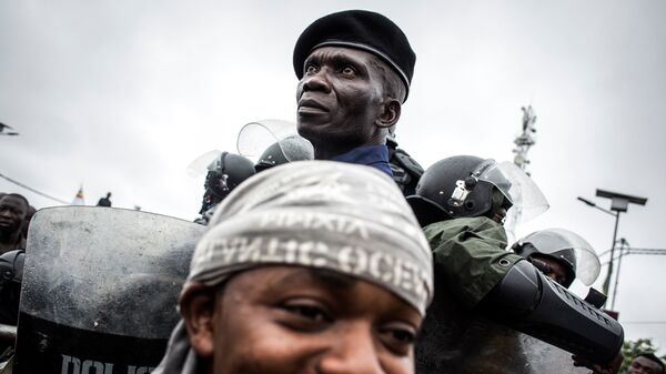 Полицейский охраняет сторонников Национального движения Конго Феликса Чисекеди и Виталия Камерхе на улице Киншаса 