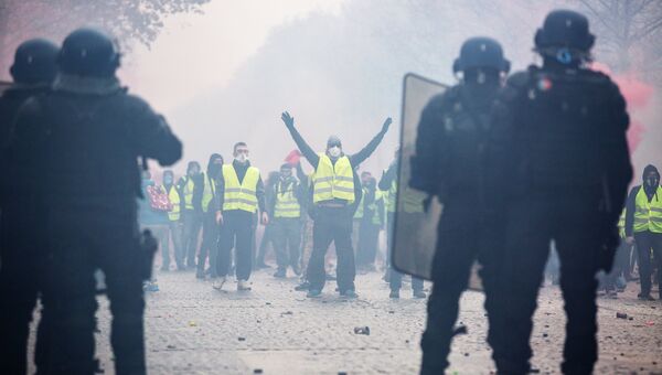 Сотрудники правоохранительных органов и активист во время протестной акции движения автомобилистов желтые жилеты в Париже. 1 декабря 2018