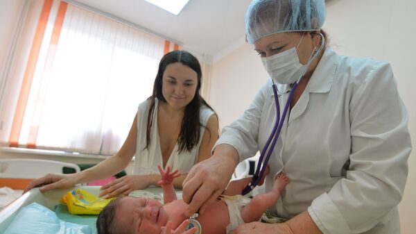 Врач проводит медицинский осмотр новорожденного. Архивное фото