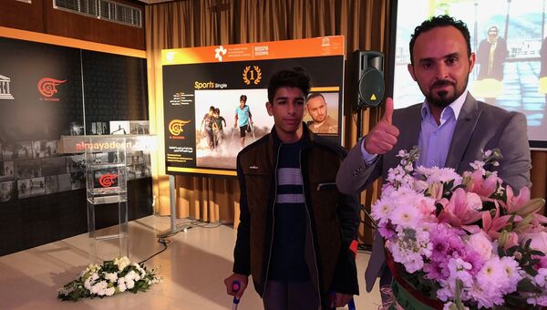 Победитель конкурса в номинации спорт иракский фотограф Таисир Мехди и герой его фотографии мальчик Касим на фоне самой фотографии. 3 декабря 2018