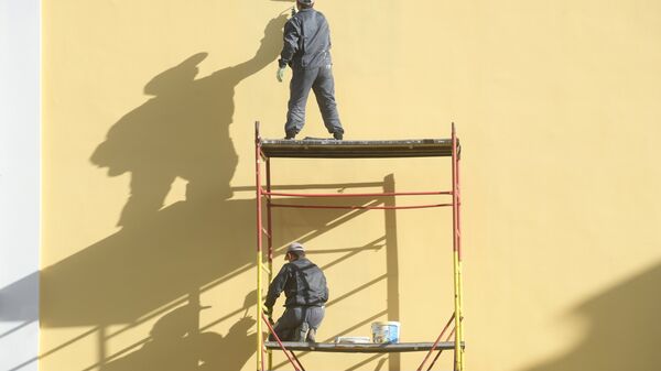 Рабочие красят фасад здания на одной из улиц Москвы