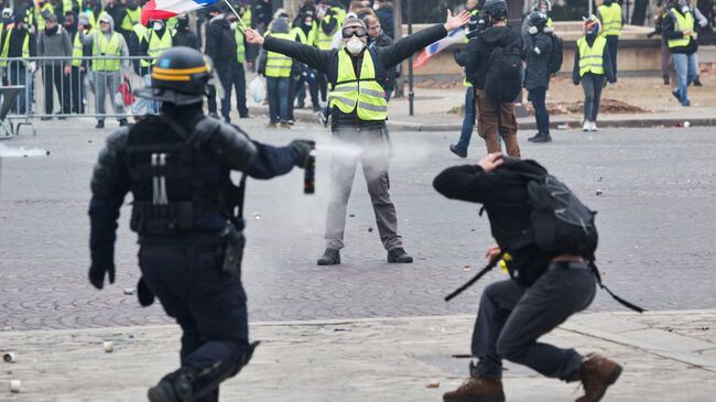 Сотрудник правоохранительных органов и активисты во время протестной акции движения желтые жилеты в Париже