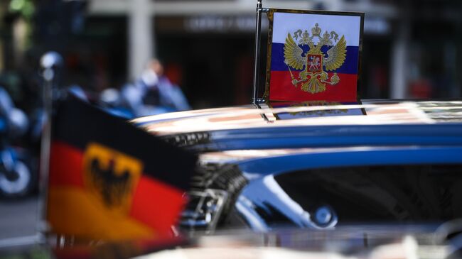 Штандарт президента РФ на автомобиле президентского кортежа и флаг Германии на автомобиле кортежа канцлера ФРГ