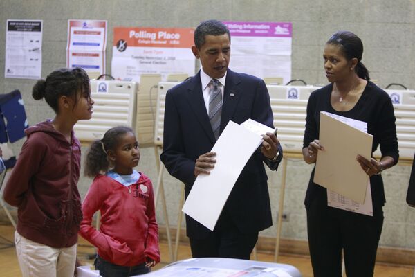 Барак Обама и его жена Мишель готовятся бросить бюллетени в урну для голосования