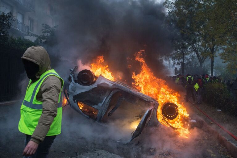 Автомобиль, горящий во время протестной акции движения автомобилистов желтые жилеты, выступавшего с требованием снижения налогов на топливо, в районе Триумфальной арки в Париже