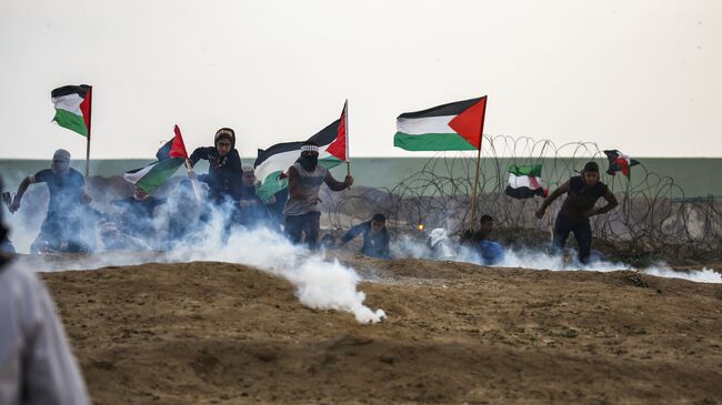 Палестинцы во время столкновений на границе с Израилем к востоку от города Газа. 7 декабря 2018 