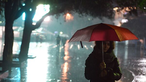 Девушка под зонтом на одной из улиц Ялты во время ливня
