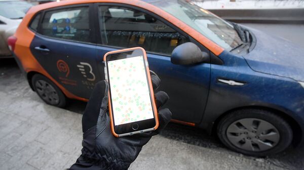 Пользователь каршеринга просматривает через приложение на смартфоне доступные автомобили
