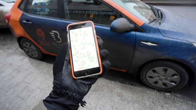 Пользователь каршеринга просматривает через приложение на смартфоне доступные автомобили