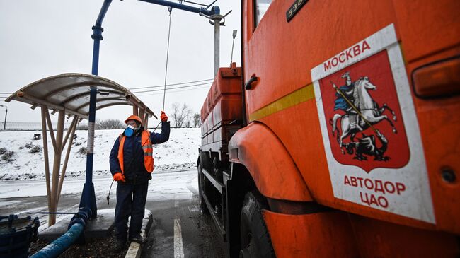 Сотрудник ГБУ Автомобильные дороги заправляет жидкий противогололедный материал в автомобиль