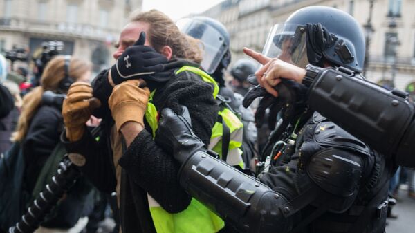 Сотрудники полиции задерживают участника акции протеста движения автомобилистов желтые жилеты в Париже.