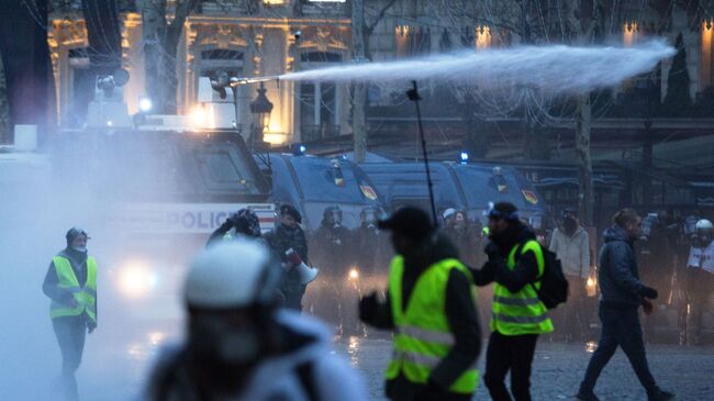 Полиция применяет водометы во время акции протеста желтые жилеты в Париже. 16 декабря 2018