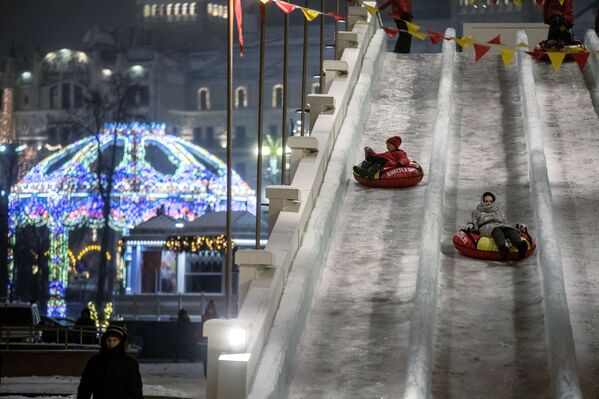 Дети катаются на ледяной горке на площади Революции в Москве