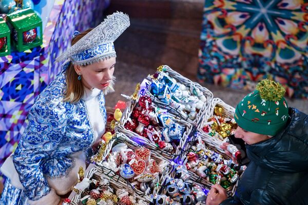 Покупатель выбирает елочные игрушки в торговом центре ГУМ в Москве
