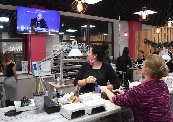 Женщины смотрят прямую трансляцию ежегодной большой пресс-конференции президента РФ Владимира Путина в салоне красоты во Владивостоке