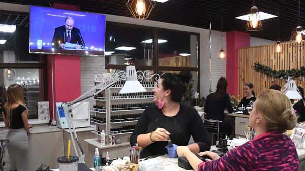 Женщины смотрят прямую трансляцию ежегодной большой пресс-конференции президента РФ Владимира Путина в салоне красоты во Владивостоке