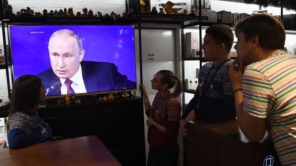 Люди смотрят прямую трансляцию ежегодной большой пресс-конференции президента РФ Владимира Путина в магазине во Владивостоке