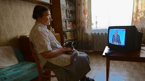 Пенсионерка смотрит прямую трансляцию ежегодной большой пресс-конференции президента РФ Владимира Путина