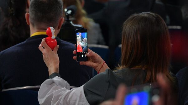Журналистка фотографирует неваляшку во время ежегодной большой пресс-конференции президента РФ Владимира Путина 