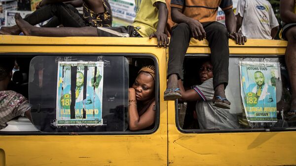 Пассажиры наблюдают за демонстрацией сторонников оппозиции в Киншасе