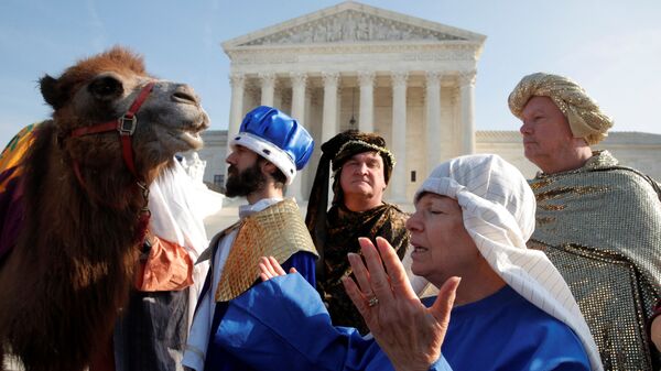 Женщина совершает молитву рядом с актерами, одетыми как Три волхва в Вашингтоне, США