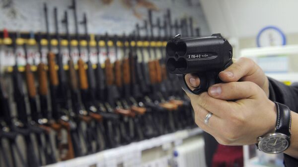 Покупатель осматривает травматический пистолет Оса в оружейном магазине