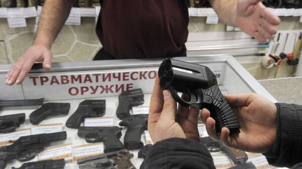 Покупатель осматривает травматический пистолет Оса в оружейном магазине 