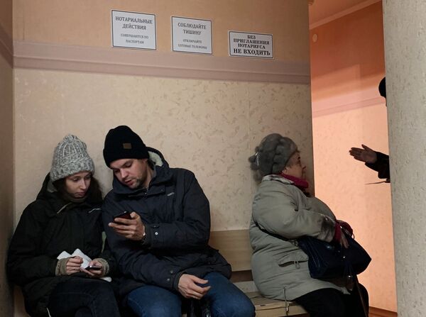 Люди сидят в очереди к нотариусу Люди сидят в очереди к нотариусу