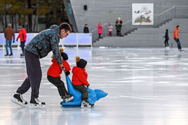 Посетители катаются на катке с искусственным льдом в парке Сокольники в Москве